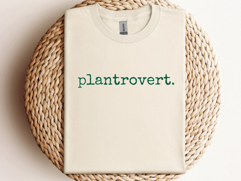 May include: A beige t-shirt with the text "plantrovert." printed in green.
