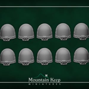 Puede incluir: Diez hombreras en miniatura grises dispuestas en dos filas de cinco. Cada hombrera tiene una parte superior redondeada y un borde inferior detallado. El logotipo de Mountain Keep Miniatures está en la parte inferior.