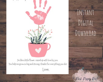Puede incluir: Tarjeta del Día de la Madre imprimible con una flor de huella de mano rosa en una taza rosa con un corazón. La tarjeta dice "Para Mamá. Soy como una pequeña flor, criada con amor por ti. Me ayudas a crecer y a ser fuerte. Gracias por todo lo que haces! Con amor."