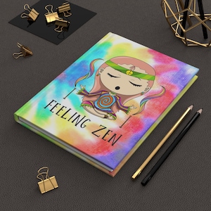 May include: A hardcover notebook with a tie-dye background in shades of pink, blue, yellow, and purple. The cover features a cartoon character in a meditation pose with a green headband and the black text "I FEELING ZEN" printed below.
