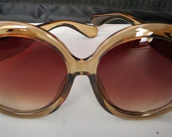 May include: A pair of large, round, brown sunglasses with a gradient lens. The sunglasses have a tortoise shell pattern on the frame.