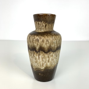 Könnte beinhalten: Eine braune und beige Keramikvase mit einem strukturierten, geschichteten Design. Die Vase hat einen schmalen Hals und einen breiteren Körper mit einem dunkelbraunen Sockel. Der Farbverlauf geht von Dunkelbraun zu Beige über und schafft ein einzigartiges Dekorationsstück.