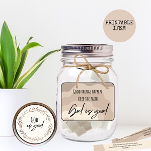 May include: A glass jar with a brown and white label that says "Good Things Happen Keep the Faith God is good". The jar is filled with small pieces of paper. There is a smaller jar with a brown and white label that says "God is good" on the lid.
