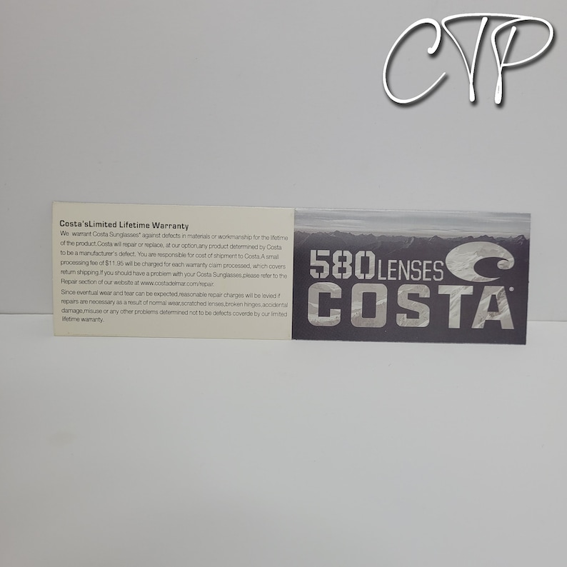 Op de afbeelding: Een witte kaart met tekst met details over de beperkte levenslange garantie van Costa. De kaart staat naast een donkergrijze kaart met de tekst "580 Lenses Costa" in het wit. De afbeelding heeft een witte achtergrond.