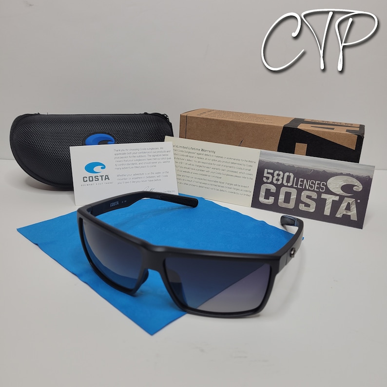 Op de afbeelding: Zwarte Costa zonnebril met een rechthoekig montuur, op een blauwe microvezeldoek. De zonnebril wordt geleverd met een zwarte etui, een kartonnen doos en informatiekaarten. De glazen hebben een gradi&euml;nt tint.