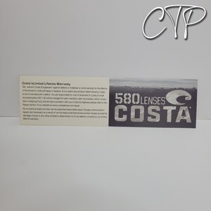 May include: A white card with text detailing Costa's Limited Lifetime Warranty sits next to a dark gray card with the words "580 Lenses Costa" in white. The warranty card explains the terms of repair or replacement for Costa sunglasses.