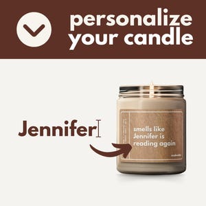 May include: A brown glass candle jar with a label that says "smells like Jennifer is reading again". The candle is lit and the jar has a black lid.