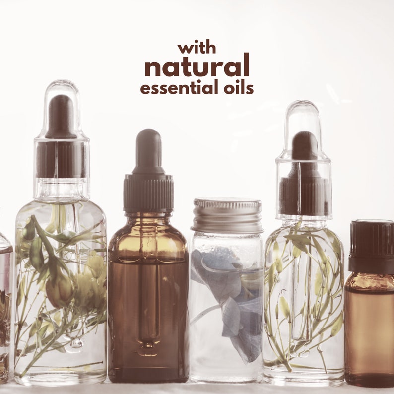 Op de afbeelding: Een rij glazen flessen met pipetten, met heldere vloeistoffen en botanische elementen. De achtergrond is wit. De tekst "with natural essential oils" wordt in bruin weergegeven. De flessen vari&euml;ren in grootte en vorm.