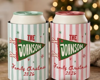 May include: Two cylindrical can coolers featuring vertical stripes in light blue and light pink. Each displays a green pennant graphic with the text THE JOHNSON, followed by the red script text Family Christmas 2026 and small star accents.