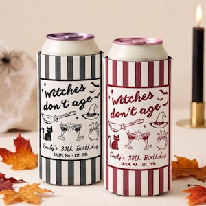 Puede incluir: Dos enfriadores de latas cilíndricos con rayas verticales y el texto Witches don't age, Emily's 30th Birthday, Salem, MA - Est. 1996. Uno es negro y blanco, el otro granate y blanco, ambos con ilustraciones de escoba, sombrero, gato y copas.