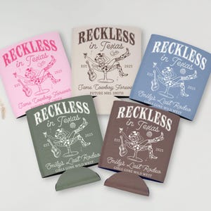 Op de afbeelding: Een verzameling van vijf drankkoelers in verschillende kleuren, elk met de tekst "Reckless in Texas" met een cowboy-thema. Extra tekst omvat "Tame Cowboy Forever" en "Emily's Last Rodeo."