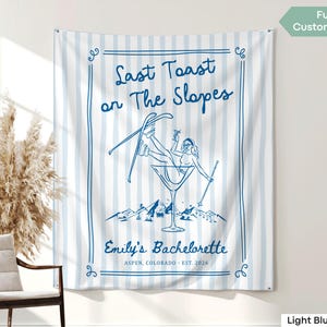 Könnte beinhalten: Ein hellblau-weiß gestreifter Wandteppich mit einer blauen Illustration. Die Illustration zeigt eine Frau in einem Martini-Glas mit Skiern, der Text lautet "Last Toast on The Slopes" und "Emily's Bachelorette, Aspen, Colorado, Est. 2026".