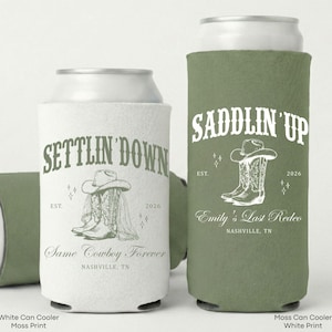 May include: White and moss green can coolers with cowboy-themed graphics. One cooler says "Settlin' Down" with a cowboy hat and boots, and the other says "Saddlin' Up" with a cowboy hat and boots. Both have text that says "Nashville, TN".
