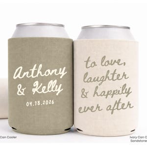 May include: Two can coolers with text. One is olive green with "Anthony & Kelly" and the date 04.18.2026 in white. The other is ivory with "to love, laughter & happily ever after" in gray. A third cooler is visible.