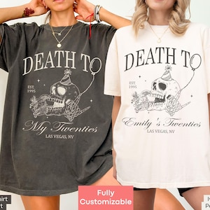 Può includere: Due donne indossano magliette oversize con una grafica di un teschio e il testo "Death to My Twenties" e "Death to Emily's Twenties". Le magliette sono disponibili nei colori pepe e avorio.