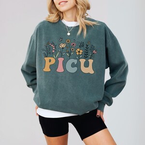 PICU nurse sweatshirt with a wildflower design, perfect for nursing graduates or holiday gifts for pediatric care professionals.