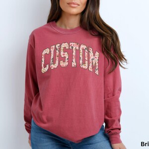 This custom long sleeve shirt features floral college-style letters, allowing you to add your own text and wear a personalized design that stands out.