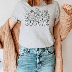Unique DnD shirt featuring flowers and dice, great for women who enjoy tabletop role-playing games.