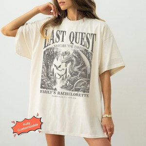 Comfort Colors® medieval bachelorette shirt with Last Quest fantasy dragon design and personalized text. A magical tee for bookish brides, Renaissance Faire bach trips, and castlecore bachelorette weekends.