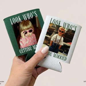 May include: Two can coolers, one dark green and one white, each featuring a printed photograph of a child wearing sunglasses. The text "LOOK WHO'S GETTING MARRIED" is printed in a bold, dark font above and below the photo on each cooler.