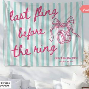 May include: A white tapestry with vertical turquoise stripes and the text "last fling before the ring" in pink script. A pink bow and rings graphic is included. The text "EMILY'S BACHELORETTE" is also present.