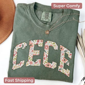 May include: A green t-shirt with a floral design spelling out the name "CECE" in a vintage collegiate style.