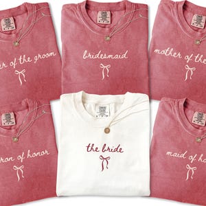 Bridal party shirts laid flat highlighting elegant lettering and soft fabric. Created for matching bridesmaid outfits and meaningful wedding party gifts.