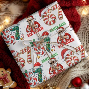 May include: A wrapped present with Christmas-themed wrapping paper. The white paper has a repeating pattern of Santa Claus with sunglasses, candy canes, and the text "SIX SEVEN" and "SANTA SAYS". The gift is tied with twine.