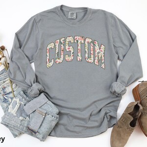 Create a one-of-a-kind look with this custom long sleeve t-shirt, where you can add your own text to the floral design for a truly unique style.