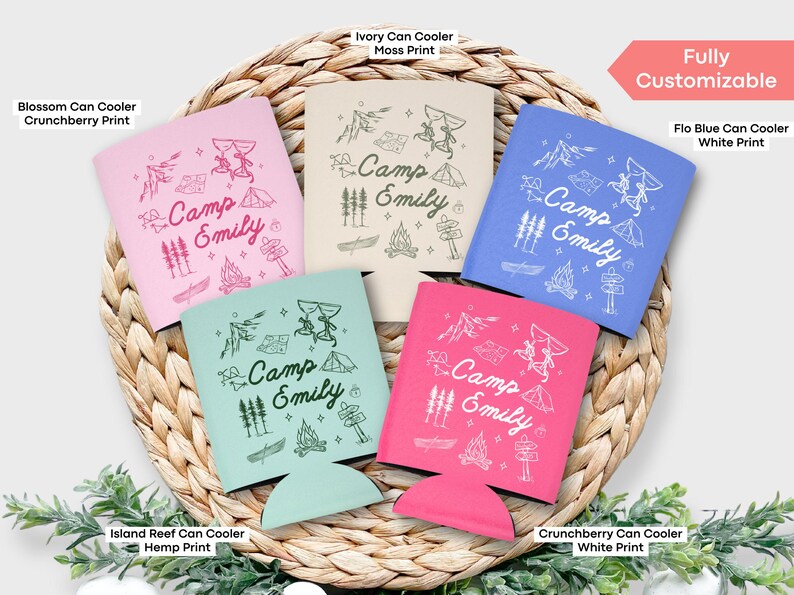 May include: Five different color can coolers with a camping theme. The coolers are all personalized with the text "Camp Emily". The colors are pink, blue, green, ivory, and white.