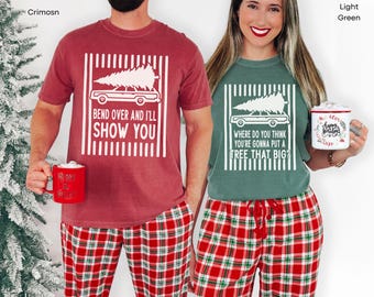 May include: A crimson t-shirt with a white graphic of a car carrying a Christmas tree and the text "BEND OVER AND I'LL SHOW YOU" and a light green t-shirt with a white graphic of a car carrying a tree and the text "WHERE DO YOU THINK YOU'RE GONNA PUT A TREE THAT BIG?"