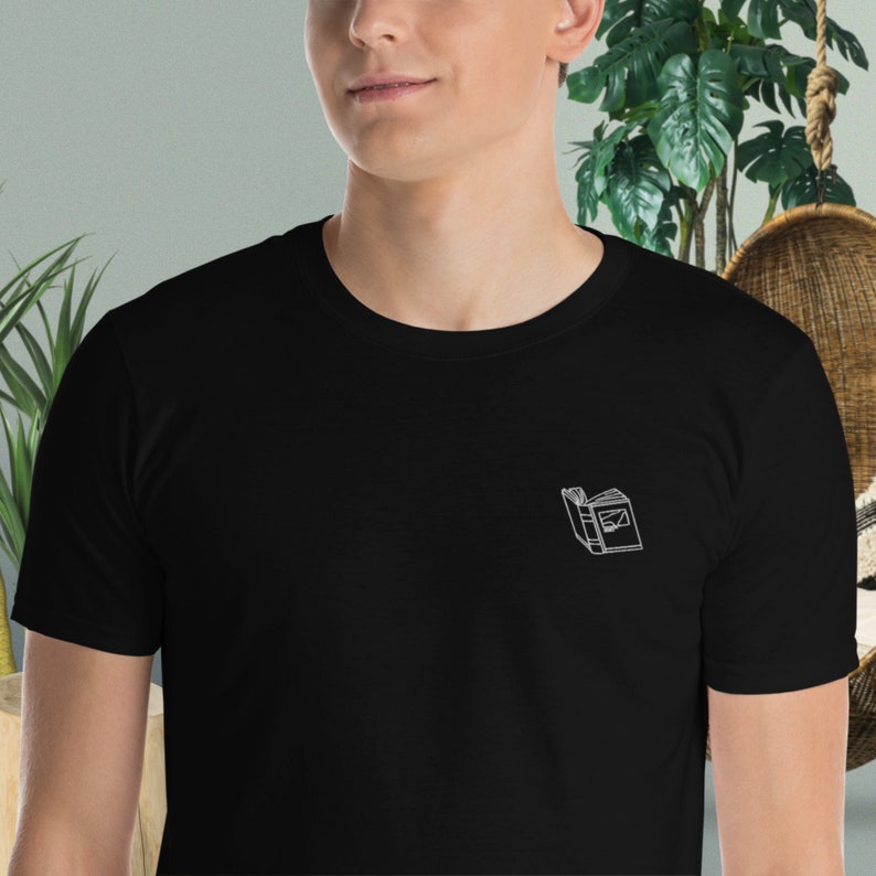 May include: A black t-shirt with a white embroidered image of a closed book.