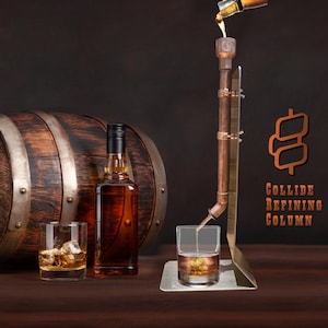 May include: A copper still with a wooden barrel and two glasses of amber liquid. The still is labeled "Collide Refining Column".
