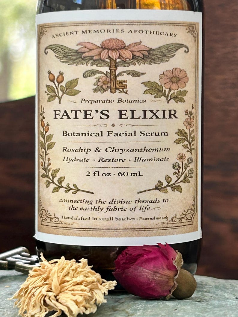 May include: A brown glass bottle with a label that reads "FATE'S ELIXIR Botanical Facial Serum." The label features botanical illustrations and text. The bottle contains 2 fl oz, which is equivalent to 60 mL. Dried flowers and a key are in the foreground.