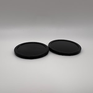 May include: Two black round coasters made of a smooth material.