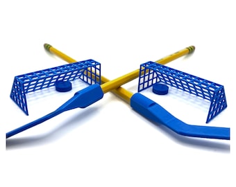May include: A tabletop hockey game set with two blue plastic hockey sticks, two blue plastic goals, and two black plastic pucks.