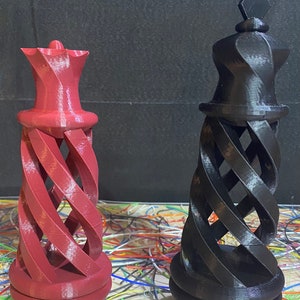 May include: Two 3D printed chess pieces, a queen and a king, with a spiral design. The queen is red and the king is black.
