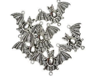 May include: Silver-toned metal bat charms with outstretched wings, detailed with textured lines. Each charm has a loop for attaching to jewelry or other crafts. The bats are arranged on a white background.