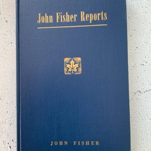 Puede incluir: Un libro de tapa dura azul marino con el título "John Fisher Reports" en letras doradas. Un logotipo de hoja de arce dorado está centrado en la portada. El nombre del autor, "John Fisher", está impreso en dorado en la parte inferior de la portada.