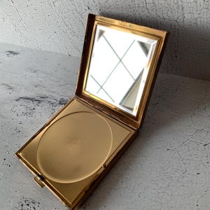 Peut inclure: Un miroir compact doré avec un couvercle à charnière et un intérieur rond et miroir. Le compact a un design simple et est en bon état.