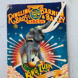 Peut inclure: Programme de cirque vintage Ringling Bros. et Barnum & Bailey avec une illustration d'éléphant. Le fond bleu porte les inscriptions "King Tusk" et "The Greatest Show on Earth".