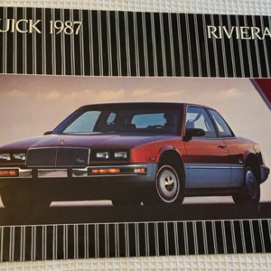 May include: A 1987 Buick Riviera brochure featuring a red and silver car with a black and white striped background. The brochure has the text "Buick 1987" and "Riviera" printed on the front.