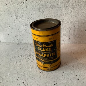 Può includere: Una lattina di metallo gialla con un'etichetta nera che recita "Black Donald Flake and Powdered Flake Graphite". L'etichetta riporta anche "Mined & Refined in Canada" e "No. 2".