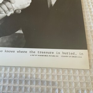 May include: A black and white photo of a man holding a gun. The text below the image reads "no knows where the treasure is buried, in 1967 BY WARNER BROS. PICTURES INC. COUNTRY OF ORIGIN U.S.A."