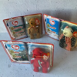 Puede incluir: Tres peluches Ty Beanie Babies de la colección International Bears II. Los osos están en su embalaje original. Los osos son Germania, Spangle y Osito. Los osos llevan ropa que representa su país de origen.