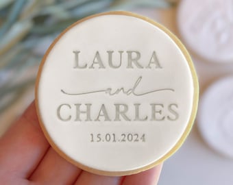 May include: White round cookie with the text "LAURA and CHARLES 15.01.2024" in gray lettering.