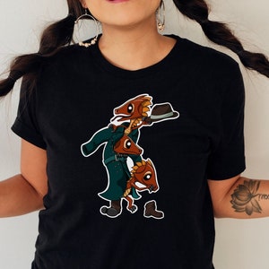 May include: Black t-shirt featuring a cartoon illustration of three anthropomorphic fish dressed as detectives. The fish are wearing hats and coats. The image is a fun and whimsical design.