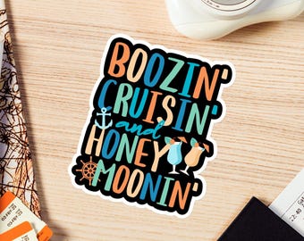 May include: A white sticker with the text "Boozin' Cruisin' and Honey Moonin'" in colorful letters. The sticker features a small anchor, a steering wheel, and two cocktail glasses.