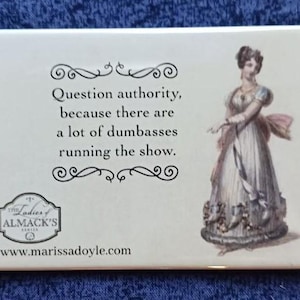 May include: Rectangular magnet with the text "Question authority, because there are a lot of dumbasses running the show." and an illustration of a woman in a long dress. The magnet also features the text "Ladies of Almack's Series" and a website address.