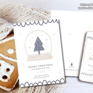 May include: A holiday card with a snow globe design, a matching digital version on a smartphone, and a gingerbread house. The card features a Christmas tree inside a snow globe, with the text "Merry Christmas and Happy New Year".